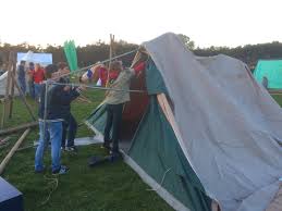 Drie scouts zetten een tent op